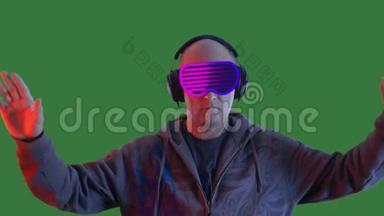 穿着虚拟现实耳机的成年男子在绿色背景上挥舞双手。 秃头男子观看vr护目镜和移动